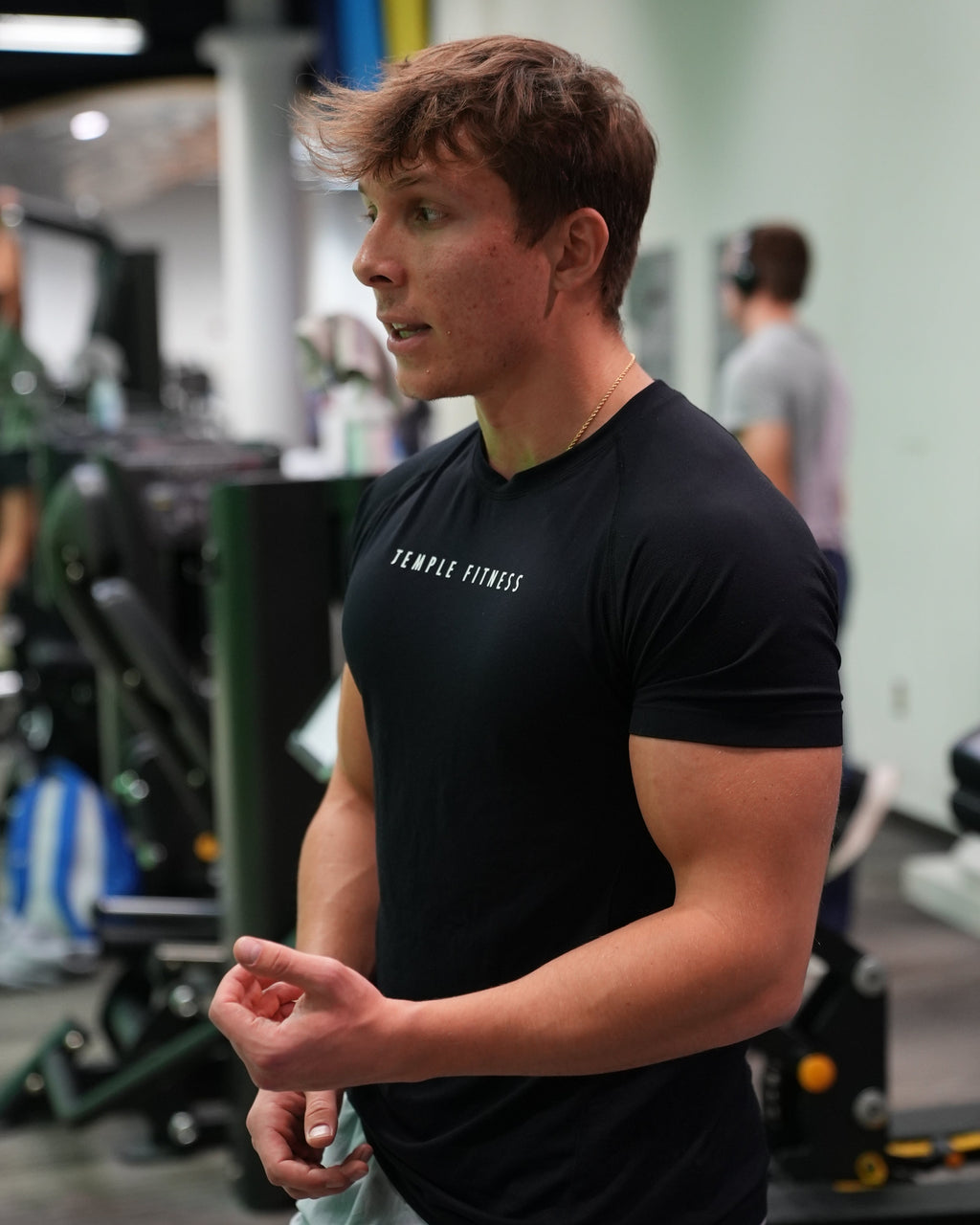 Person wearing a black t-shirt with text in a gym setting