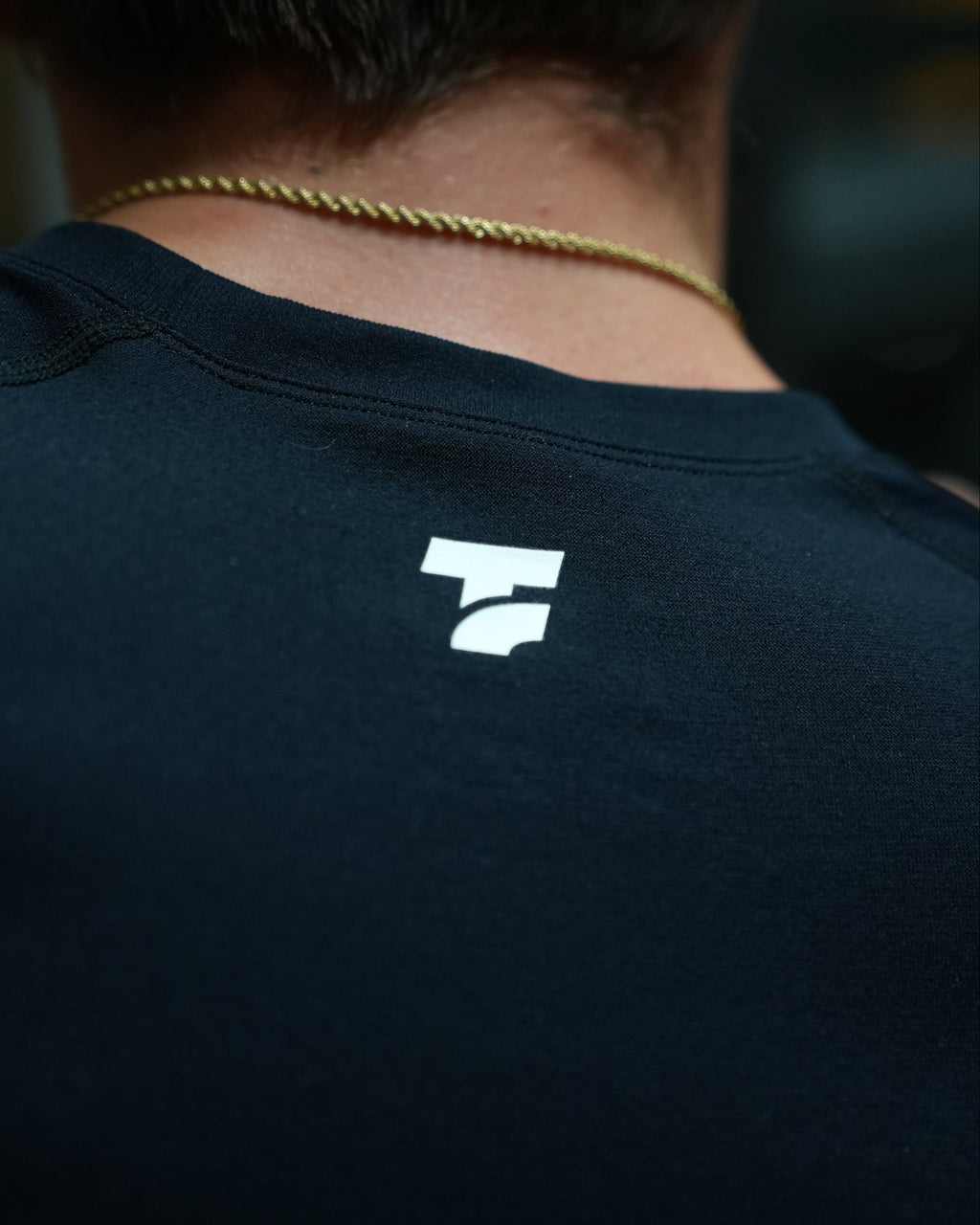 Close-up of a black shirt with a white logo on the upper back