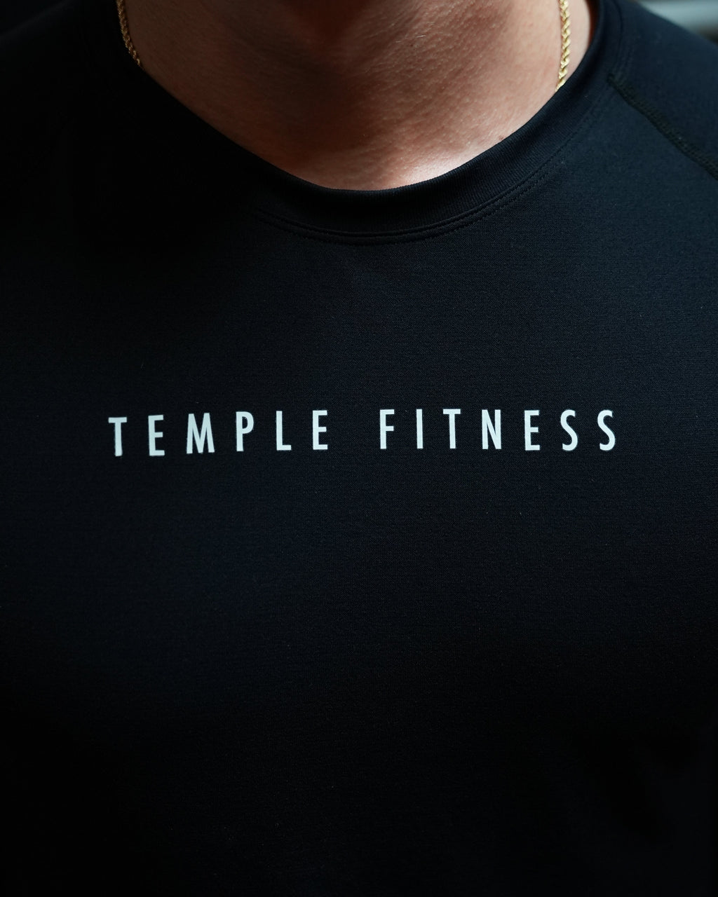 Black seemless top with 'Temple Fitness' branding on a dark background