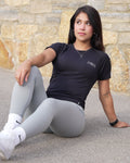 Person wearing a black t-shirt and gray leggings on a stone pavement