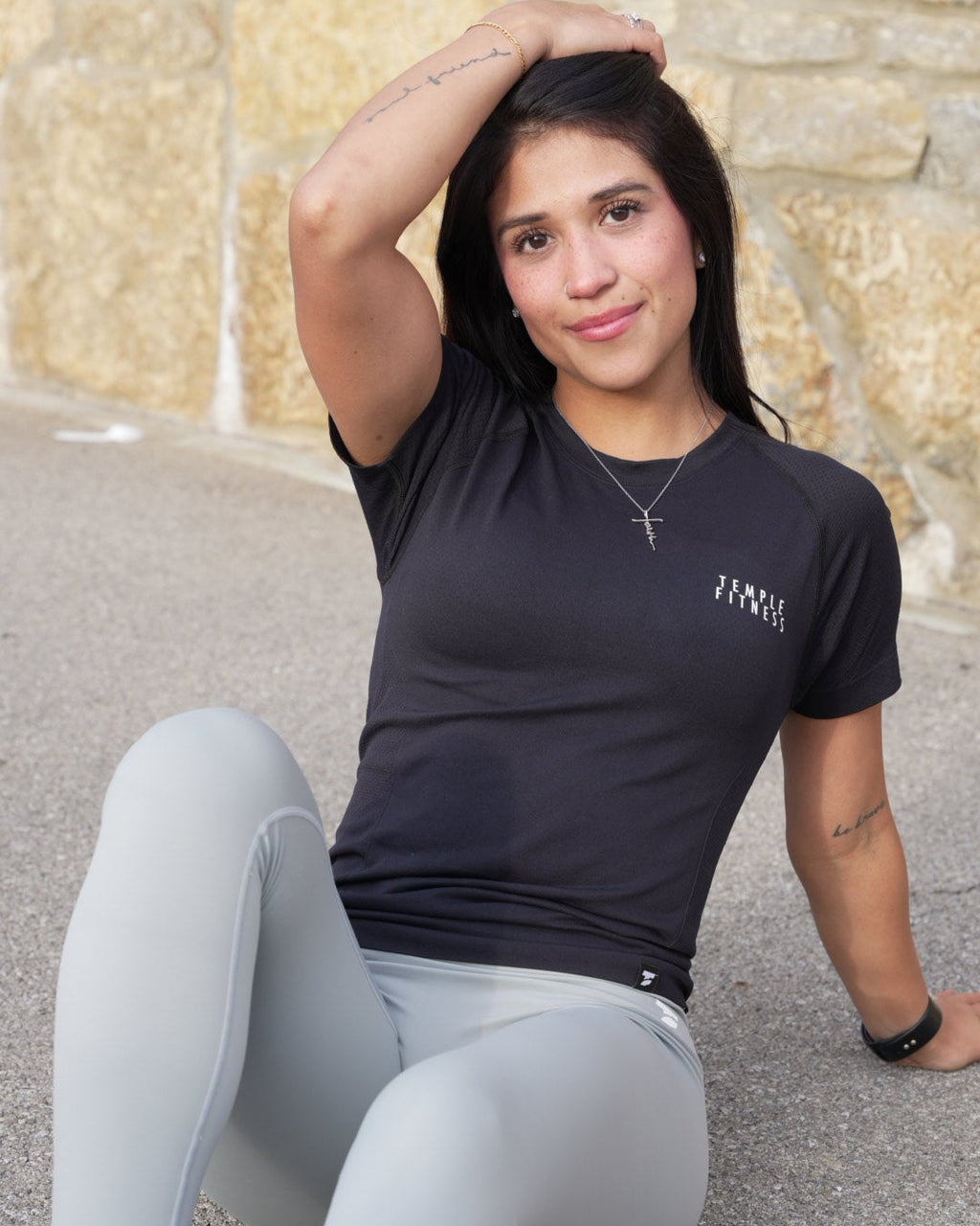 Woman in athletic wear sitting on a stone surface outdoors