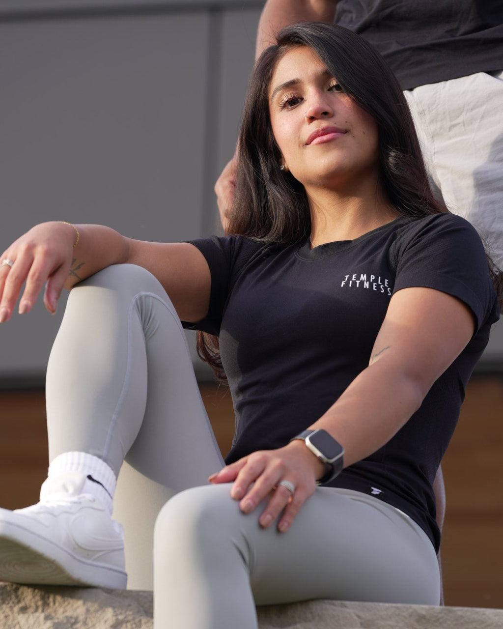 Person wearing a black shirt and gray leggings climbing a rock wall.