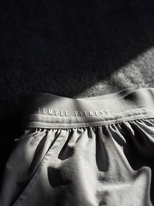 Gray athletic top with 'Temple Fitness' branding on a dark background